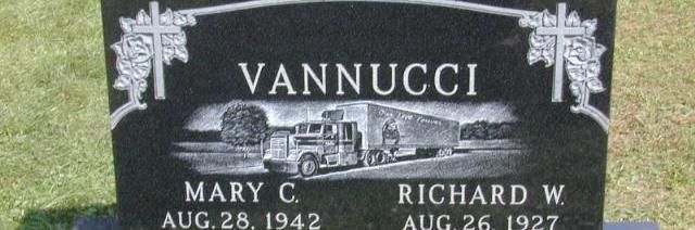Black gravestone with “Vannucci” and two memorial plaques in a grassy cemetery.