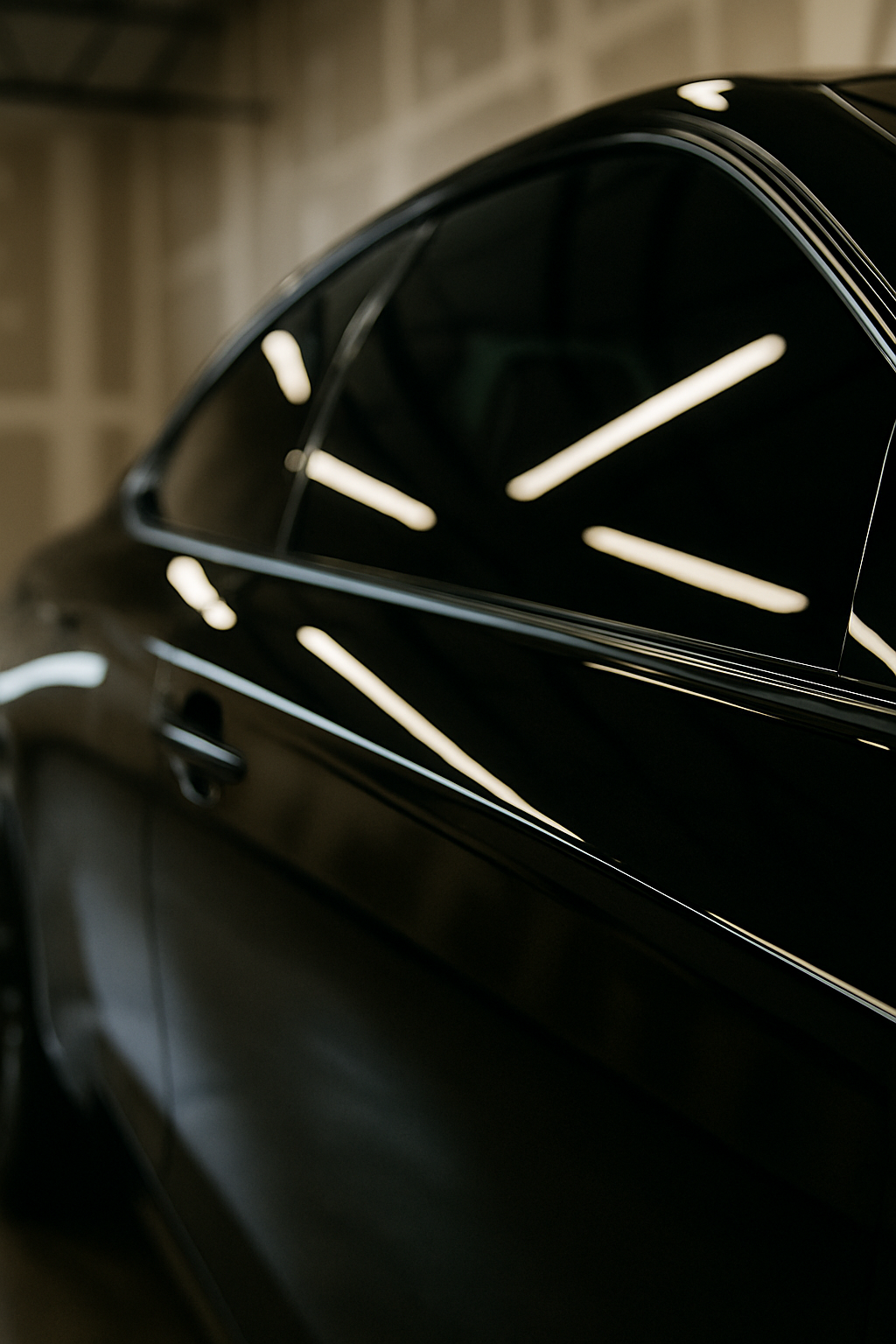 Black car side view, reflective windows, interior setting with bright lights.