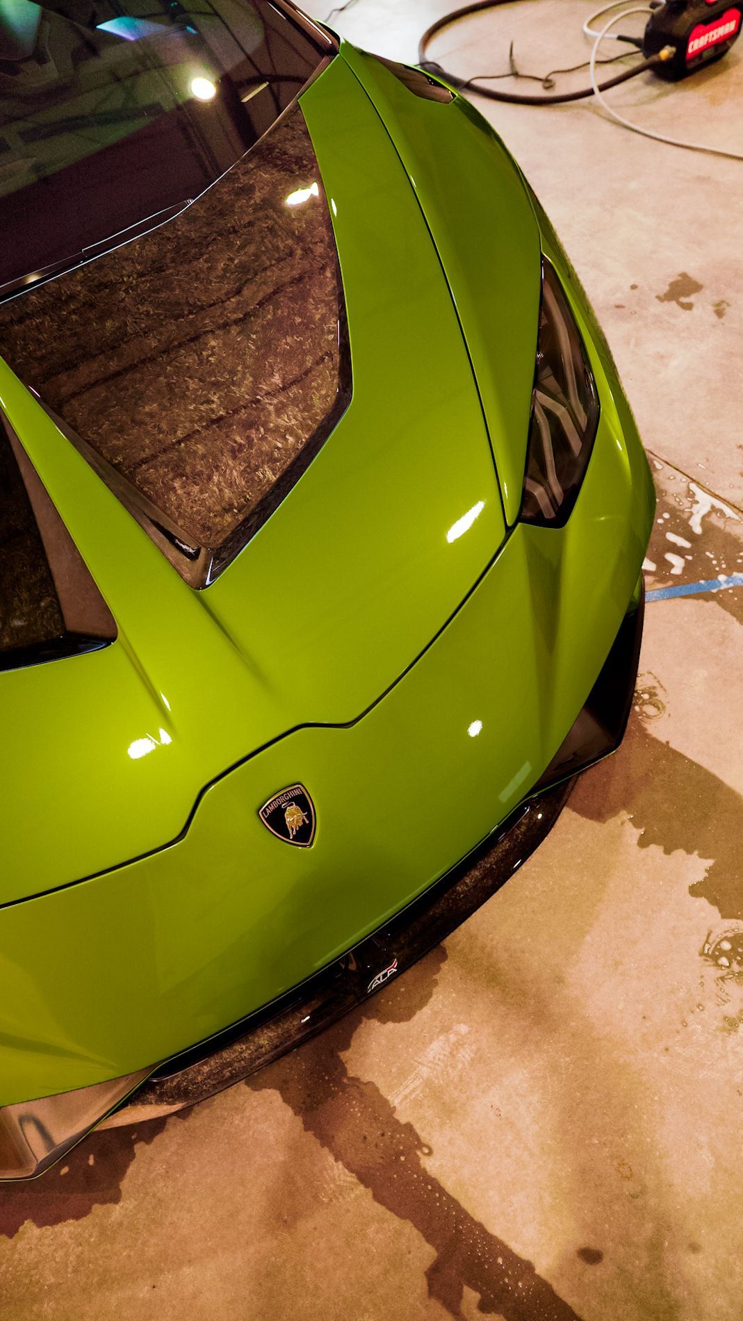 Green Lamborghini sports car, parked near a building, nighttime setting.