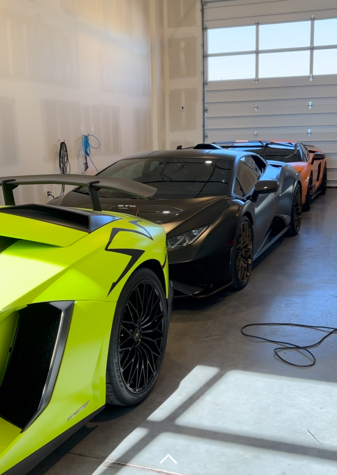 Line of Lamborghinis: lime green, black, gray, and orange cars in a garage.