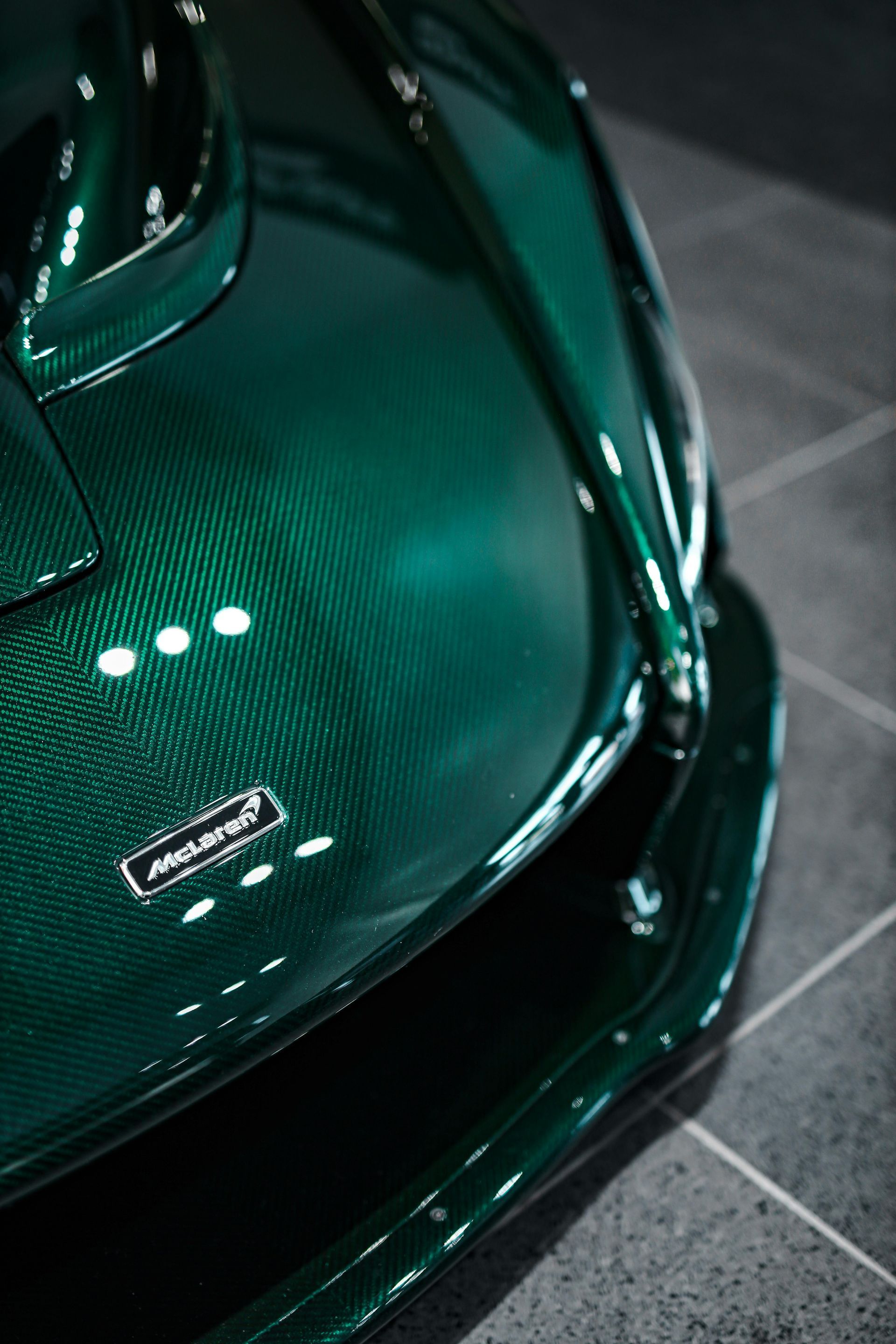 Green carbon fiber McLaren car hood detail with logo.