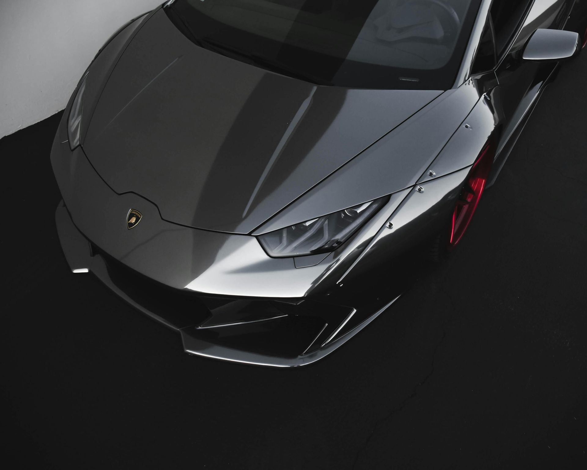 Gray Lamborghini sports car with red wheels on a black surface.