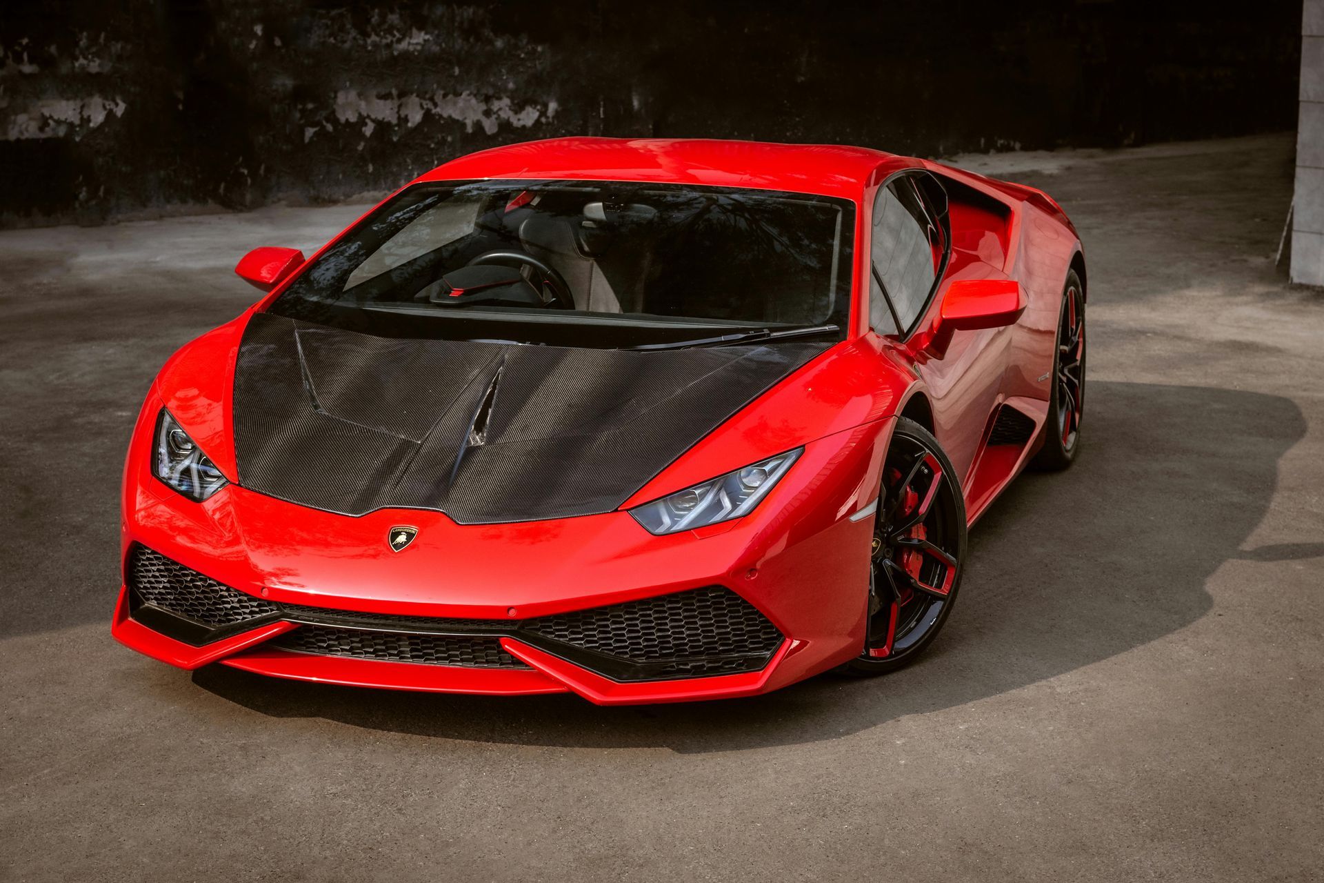 Red Lamborghini sports car with black carbon fiber hood, parked.