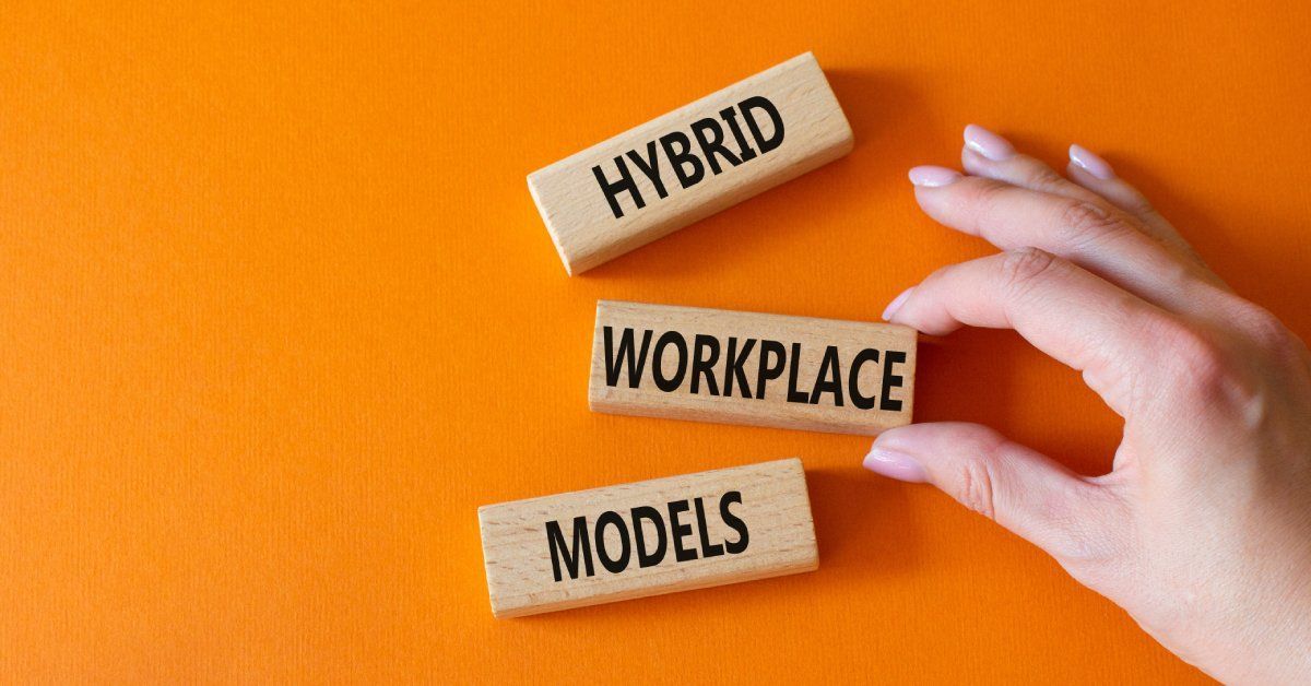  Closeup of three blocks that say “hybrid workplace models” with a hand holding one.