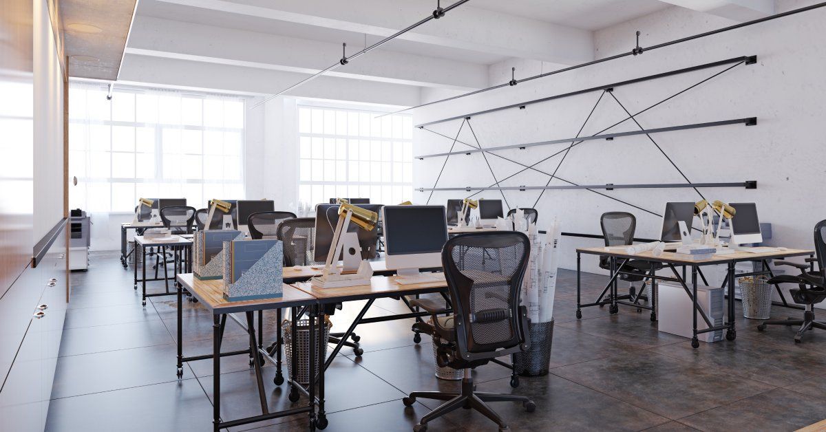 A large, modern office space with an open layout that has several desks, computers, and chairs.
