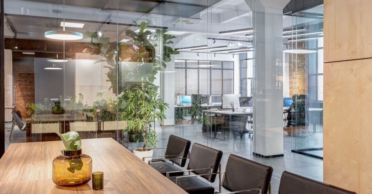 A conference room with a table and chairs has a glass wall separating it from the rest of the office.
