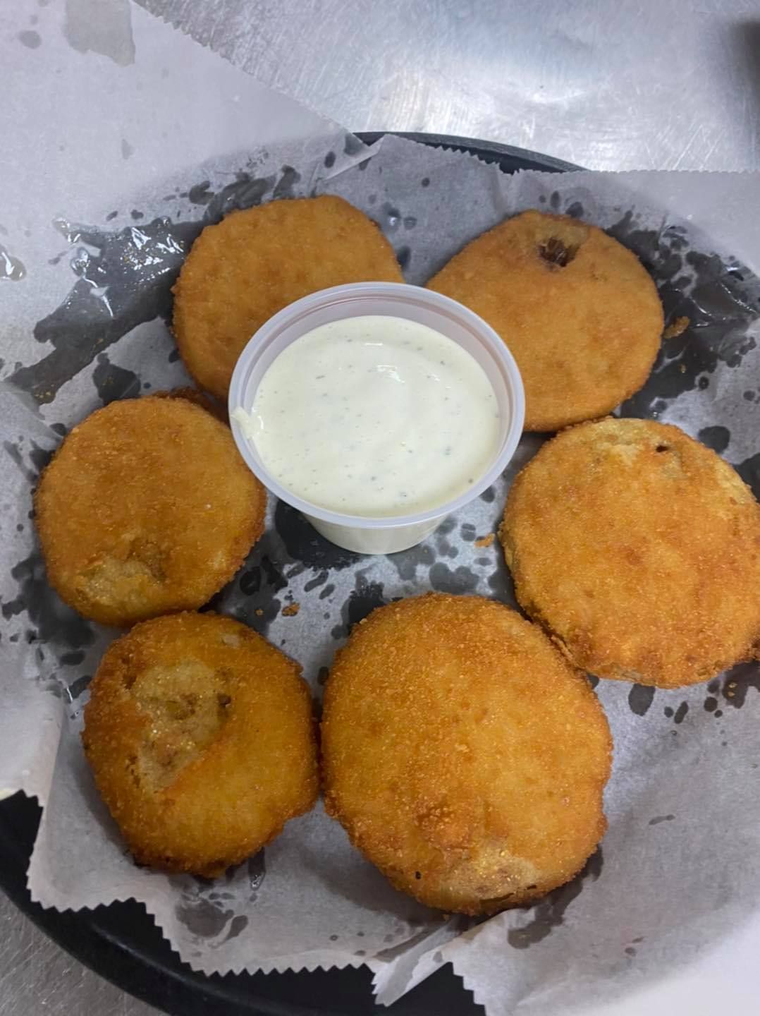 Fried green tomatoes with ranch dressing in a basket.