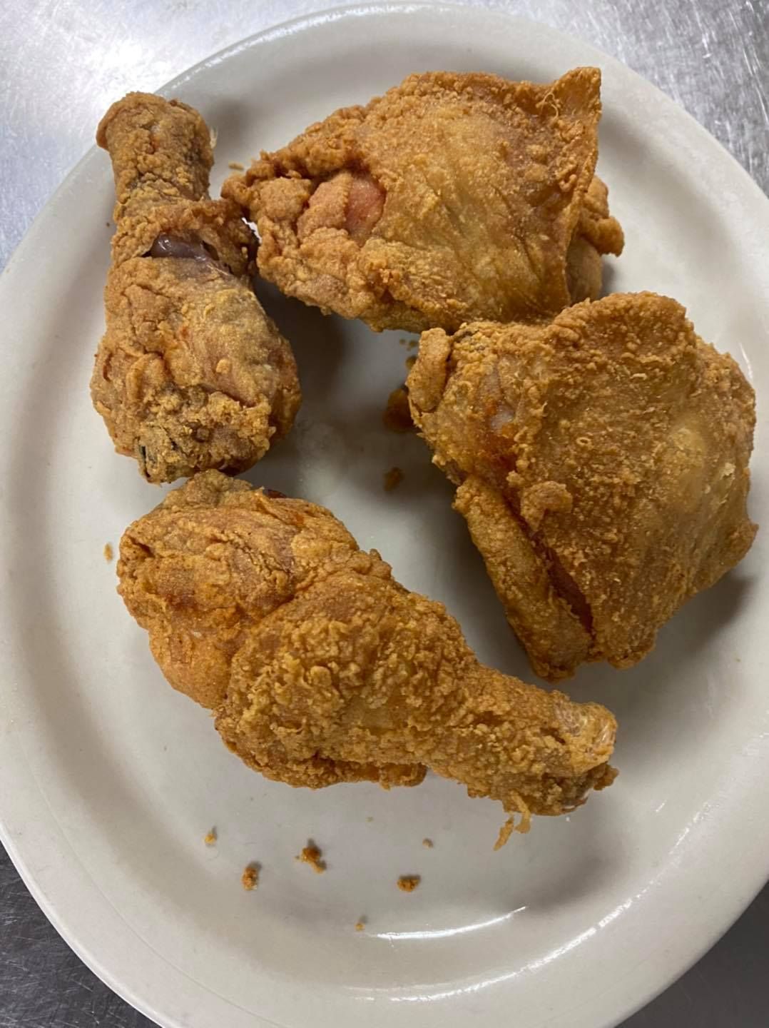 Plate of crispy, golden-brown fried chicken pieces: leg, breast, and thigh.