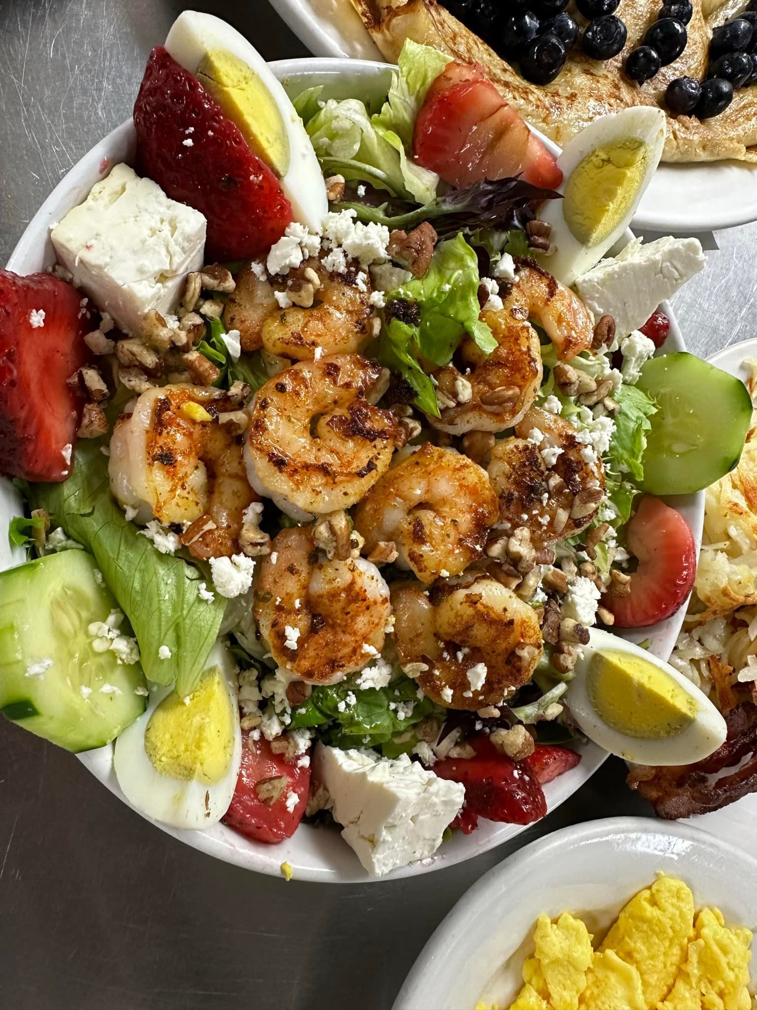 Grilled shrimp salad with strawberries, eggs, feta, and pecans.