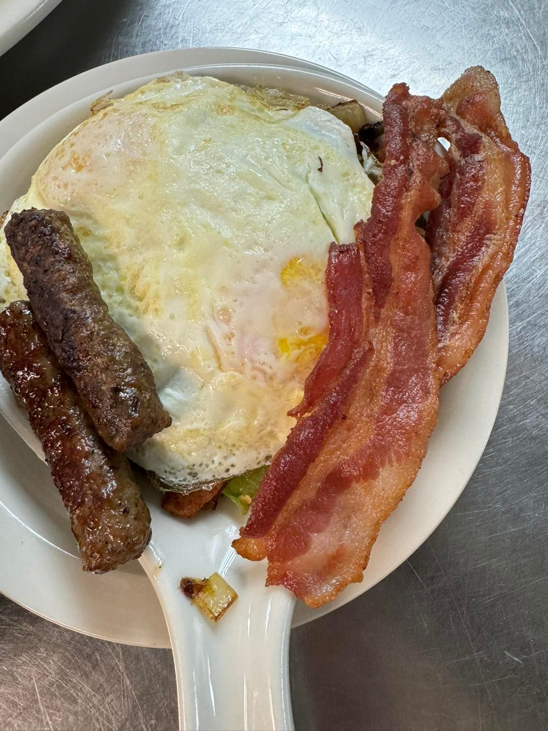 Breakfast plate with fried egg, sausage, and bacon.