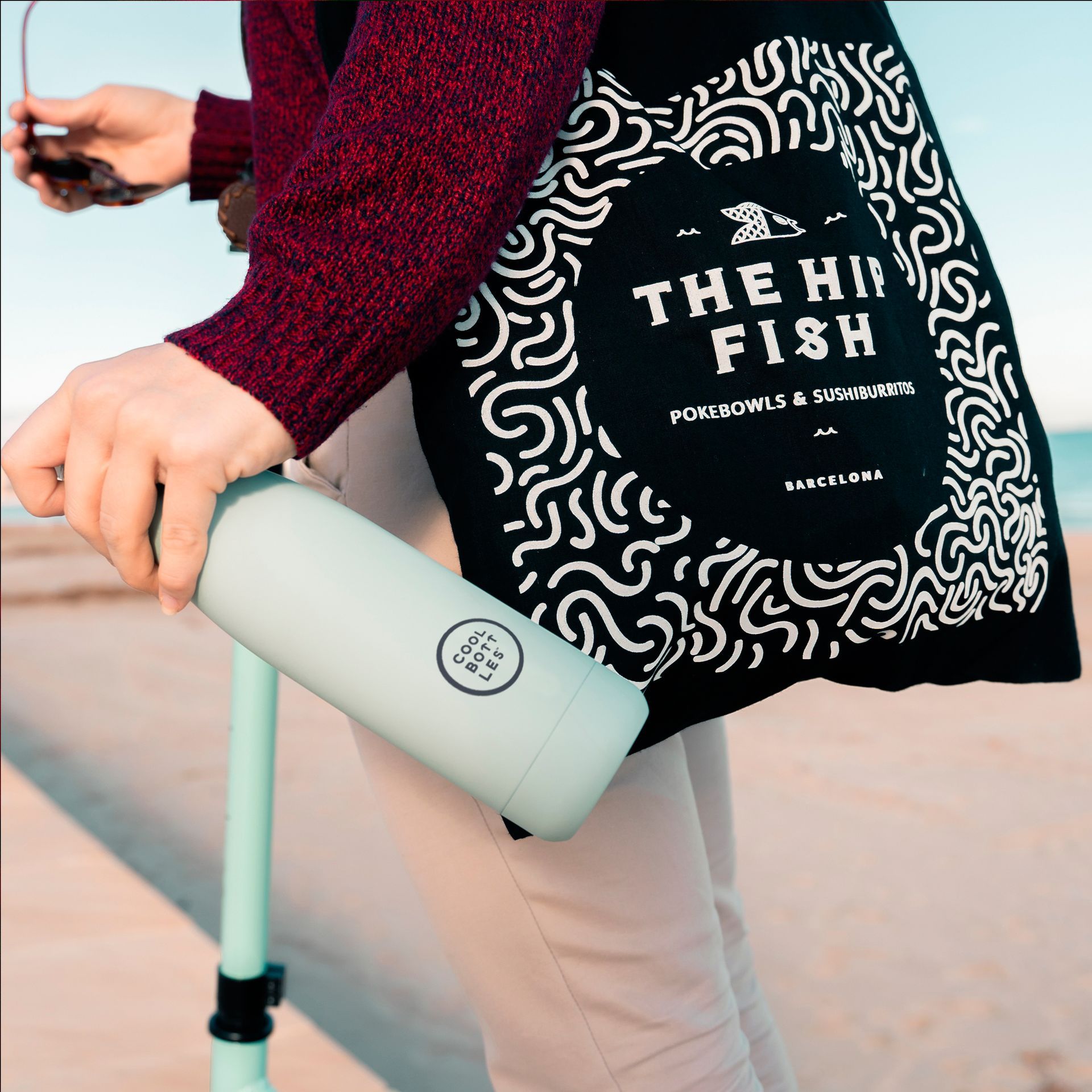 Pessoa com uma tote bag e uma garrafa térmica da Cool Bottles na mão