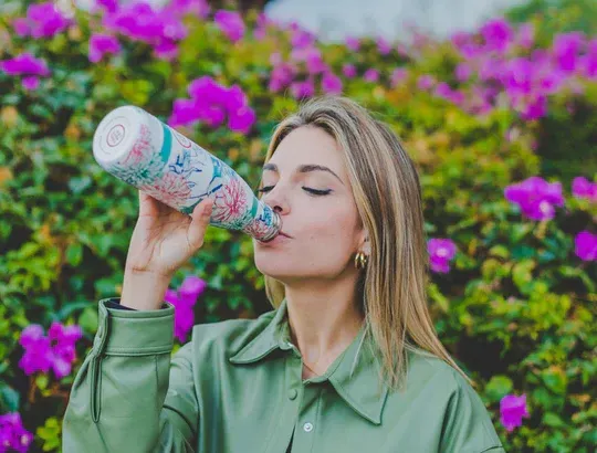 Rapariga a beber de uma garrafa térmica da Cool Bottles com flores