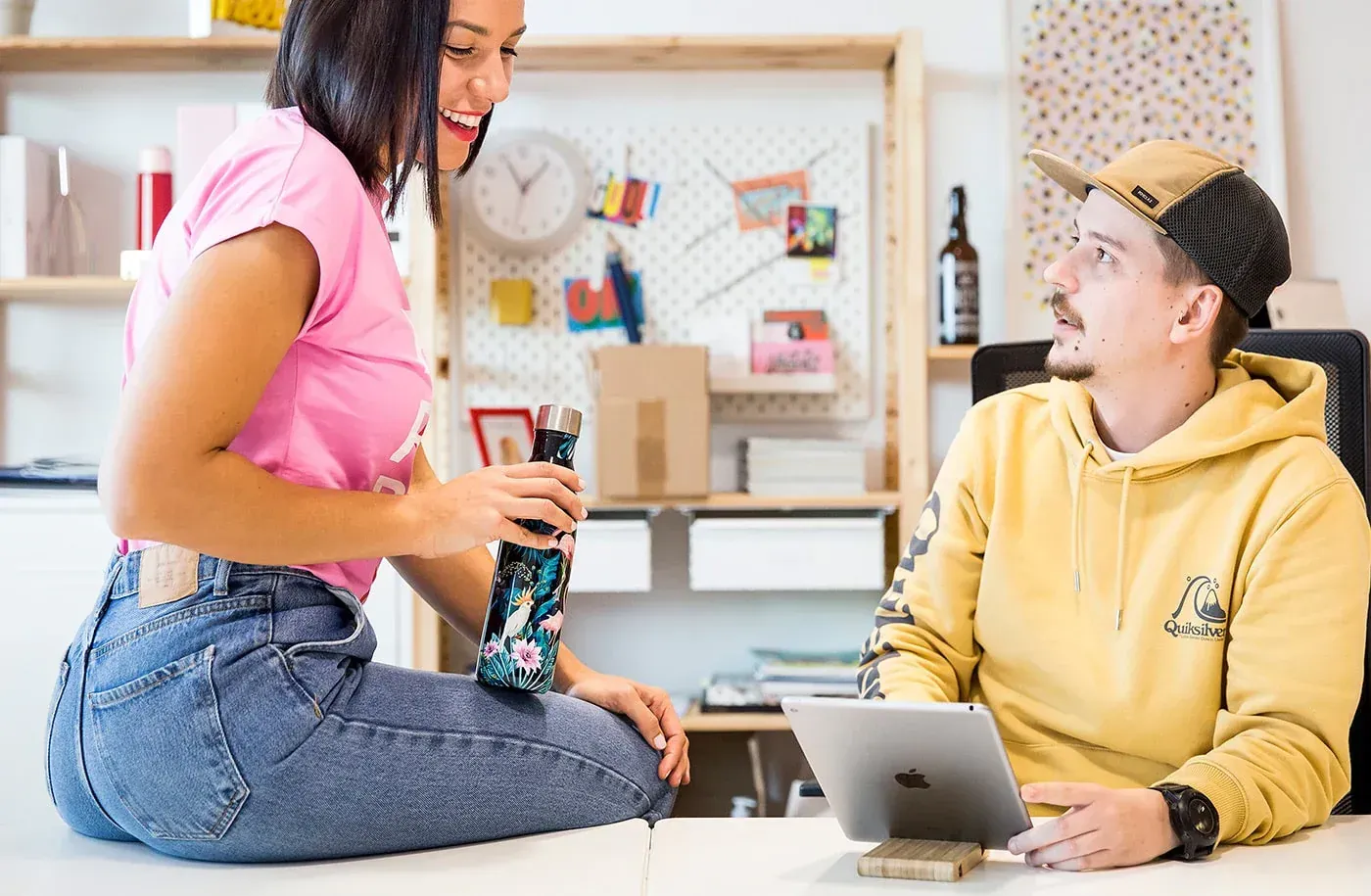 Homem e mulher em reunião com computador e garrafa térmica