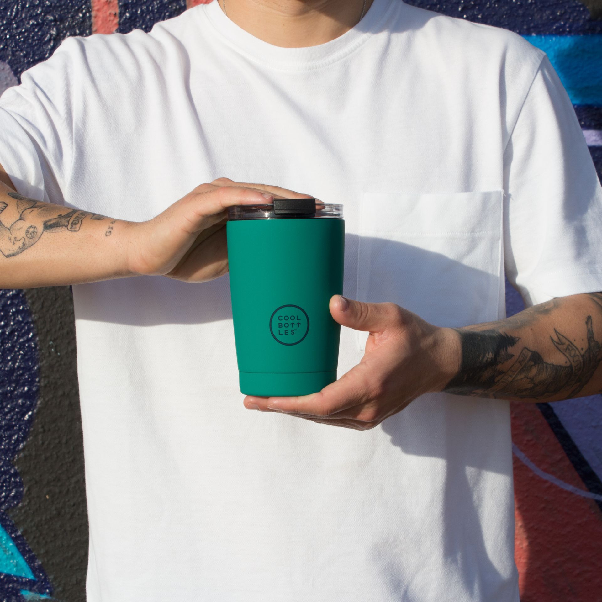 Copo térmico verde da Cool Bottles segurado nas mãos