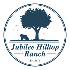 Dark blue silhouette of a tree and cow on a hill in a circle, with 