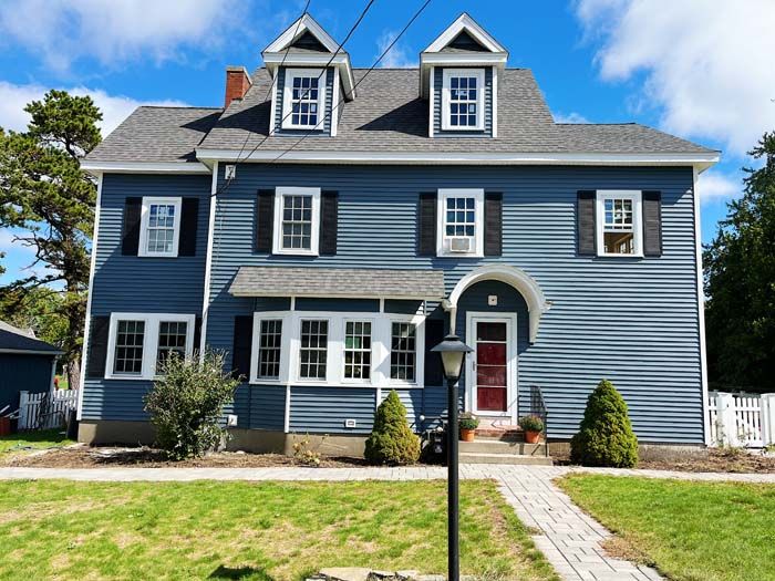 A large blue house with black shutters and a red door.