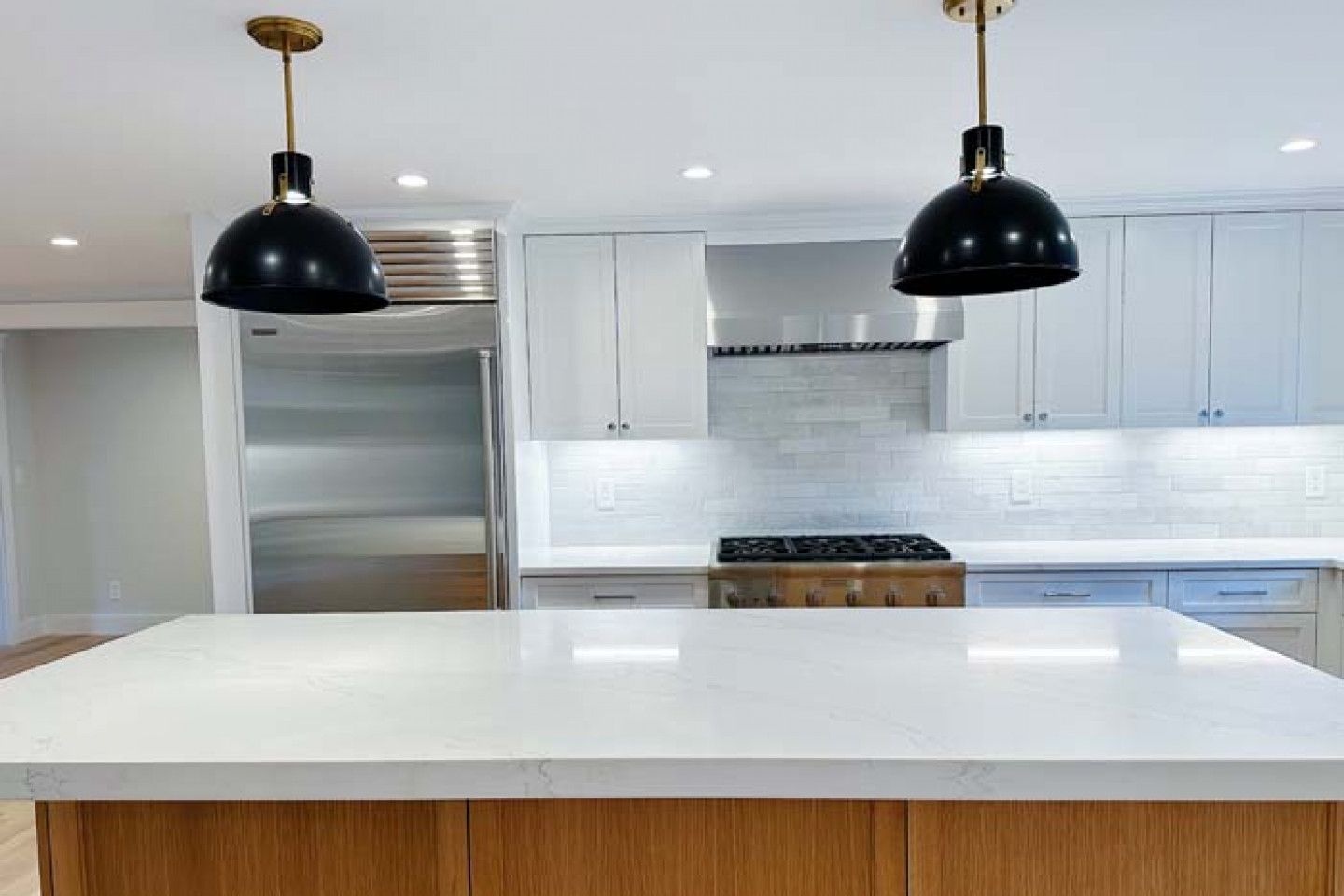 A kitchen with white cabinets, stainless steel appliances, and a large island.