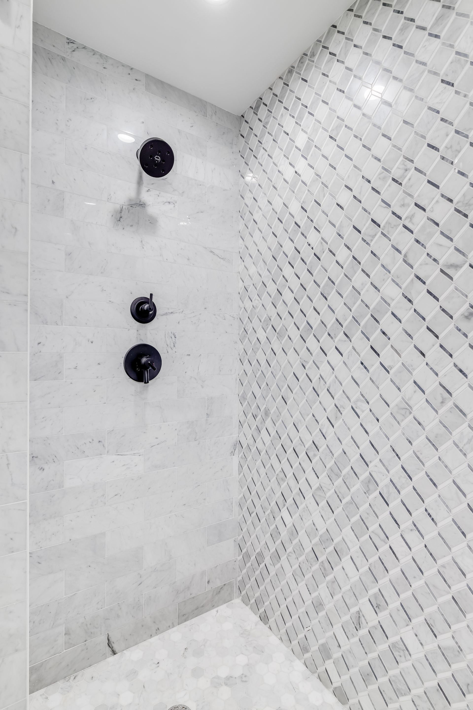 A bathroom with a walk in shower and a black shower head.