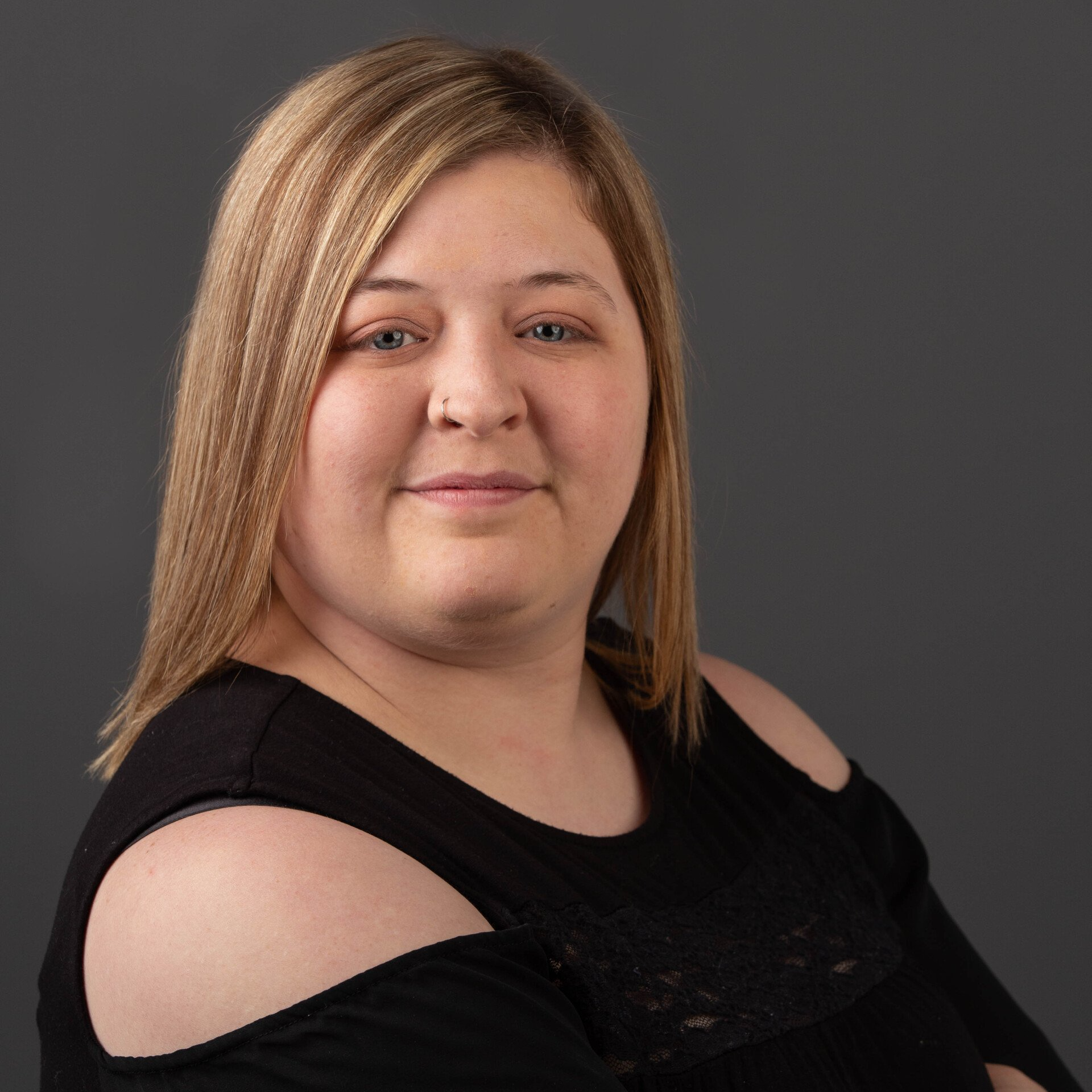 A woman with blonde hair is wearing a black off the shoulder top