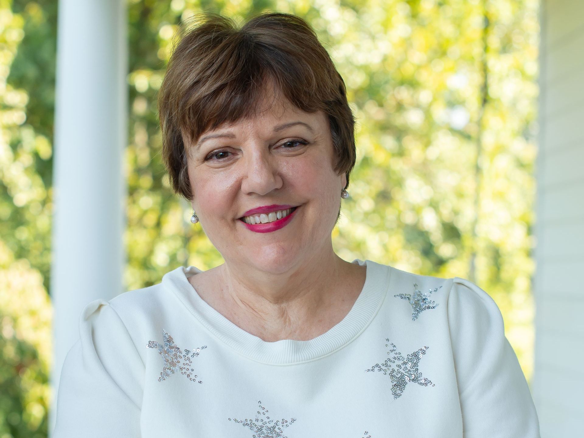 A woman is smiling and wearing a green and white shirt.