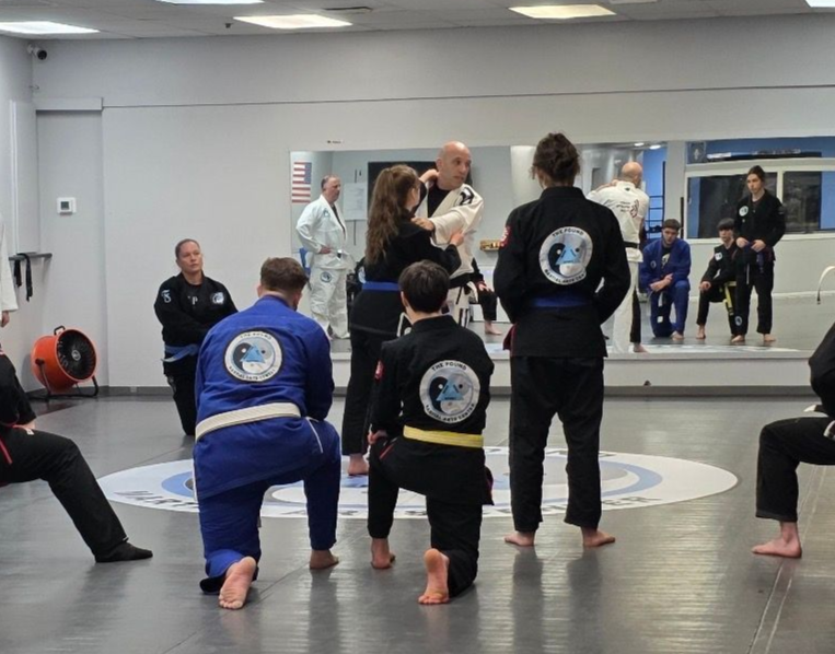 Two men grappling on a mat, one in blue, the other in black.