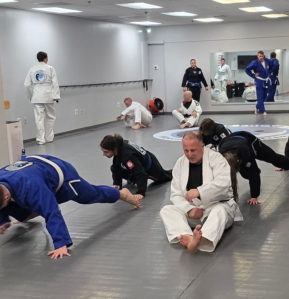 Two people practicing Brazilian Jiu-Jitsu on a mat. One is on top, applying a hold.