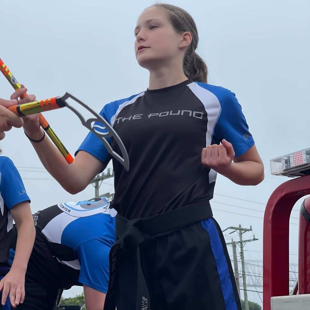 Two people practicing Brazilian Jiu-Jitsu on a mat; one in a black gi, one in a white gi, grappling.