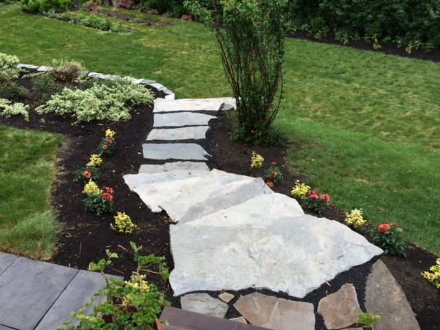 Une allée en pierre traversant un jardin verdoyant