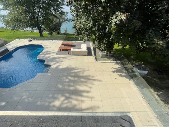 Une grande piscine est entourée d'arbres et d'un patio.