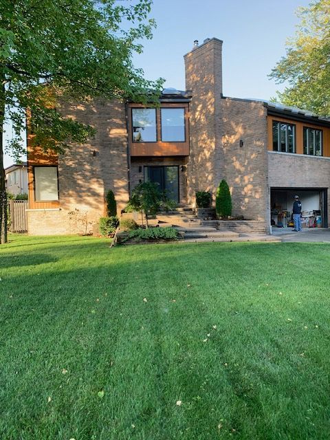 Une grande maison en briques avec une pelouse verte luxuriante devant elle