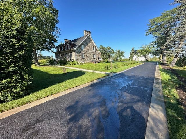 Une maison est située au bord d'une route à côté d'un champ vert luxuriant.
