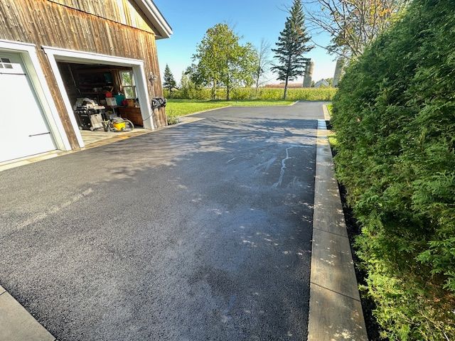 Une allée menant à un garage avec un bâtiment en bois en arrière-plan.
