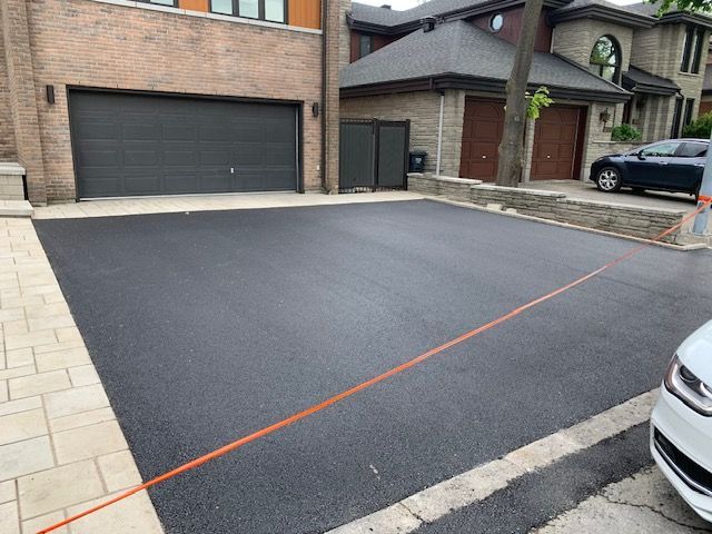 Une voiture est garée dans une allée à côté d'une maison.