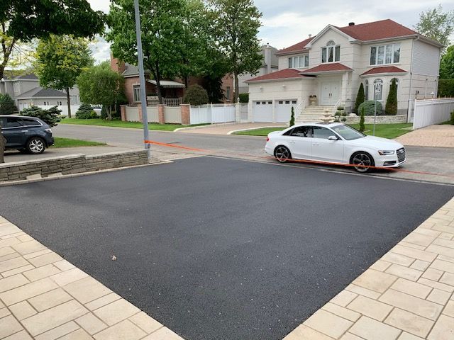 Une voiture blanche est garée dans une allée devant une maison.