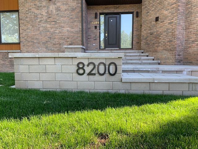 Un mur de briques avec le numéro 8200 dessus devant une maison en briques.