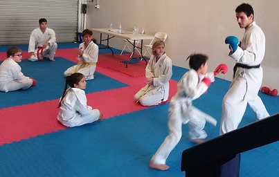 A group of kids are practicing martial arts in a gym