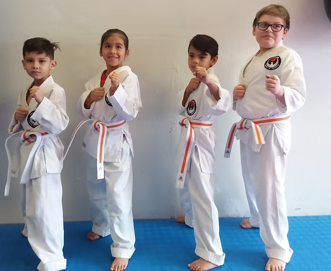 A group of young karate fighters are posing for a picture