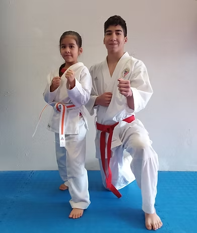 A boy and a girl are practicing karate on a blue mat.