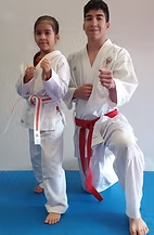 A boy and a girl are standing next to each other on a blue mat.