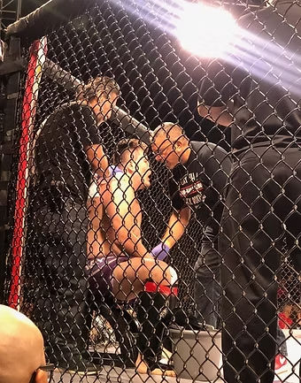 A group of people are in a cage watching a fighter
