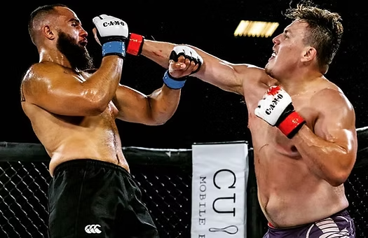 Two men are boxing in front of a sign that says cu