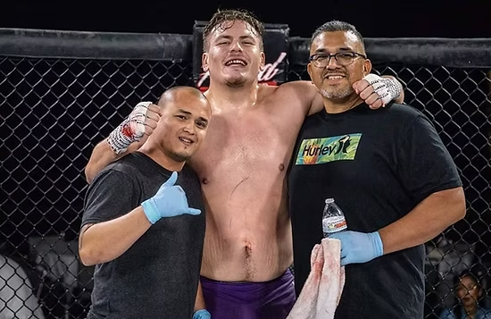 A man in a hurley shirt is standing next to two other men in a boxing ring.
