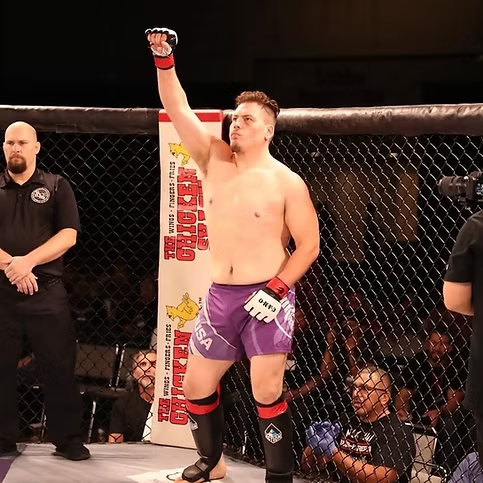 A man in a boxing ring with his fist in the air