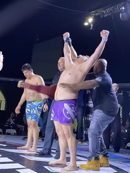 A man in purple shorts is standing on a stage with his arms in the air.