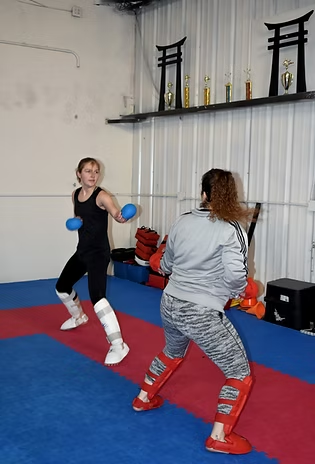 Two women are practicing martial arts in a gym.
