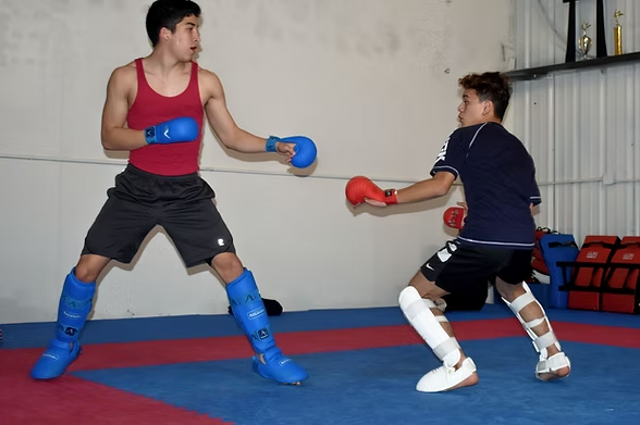 Two young men are boxing on a mat in a gym