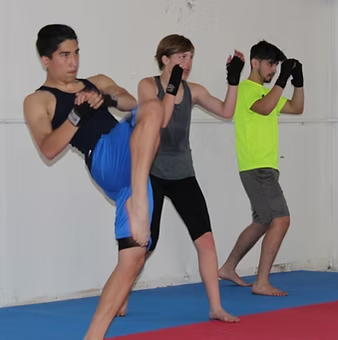 Three people are practicing martial arts in a gym