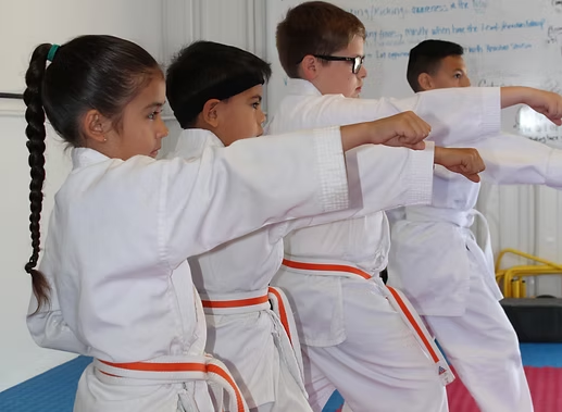 A group of children are practicing martial arts in a gym
