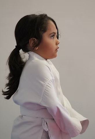 A little girl is wearing a white robe and a pink belt.