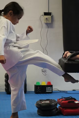 A young girl is practicing karate on a blue mat.
